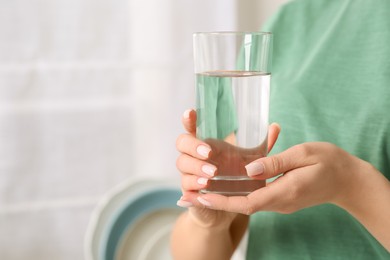 Healthy habit. Closeup of woman holding glass with fresh water indoors, space for text