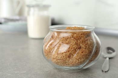 Photo of Glass bowl with brown sugar on grey table