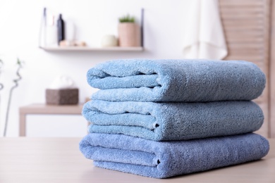 Photo of Stack of fresh towels on table in bathroom. Space for text