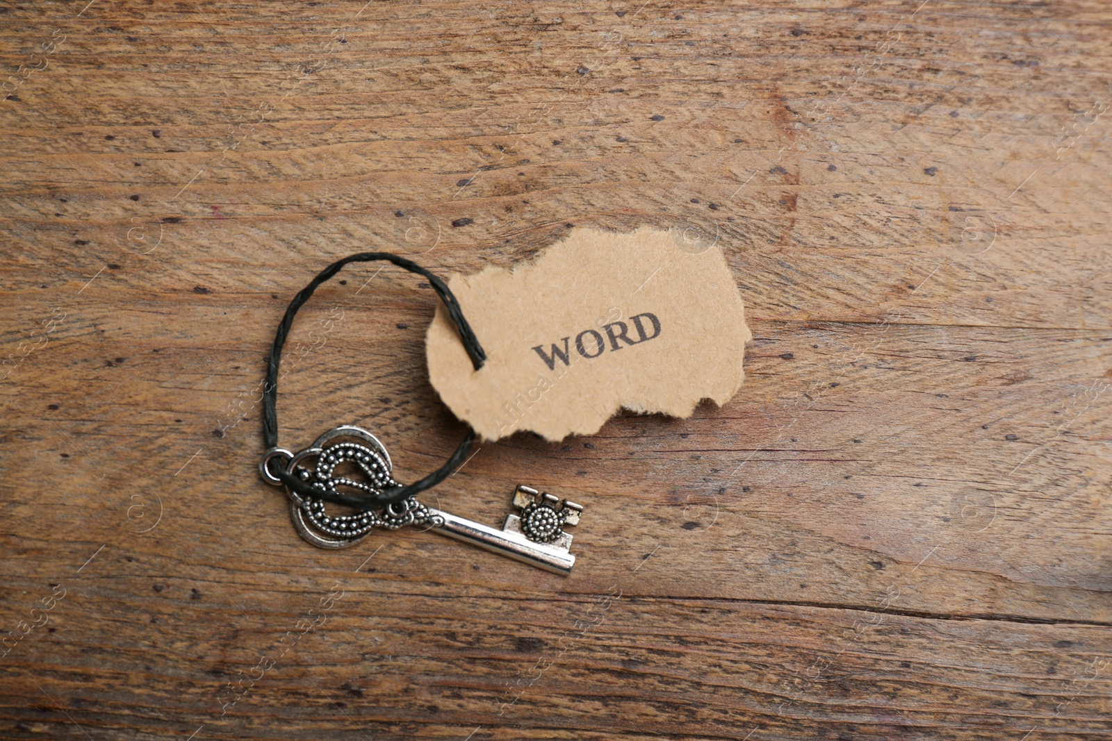 Photo of Vintage key with tag on wooden table, top view. Keyword concept