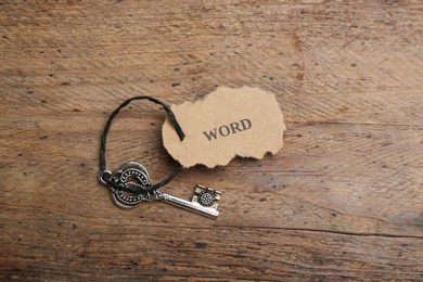 Vintage key with tag on wooden table, top view. Keyword concept