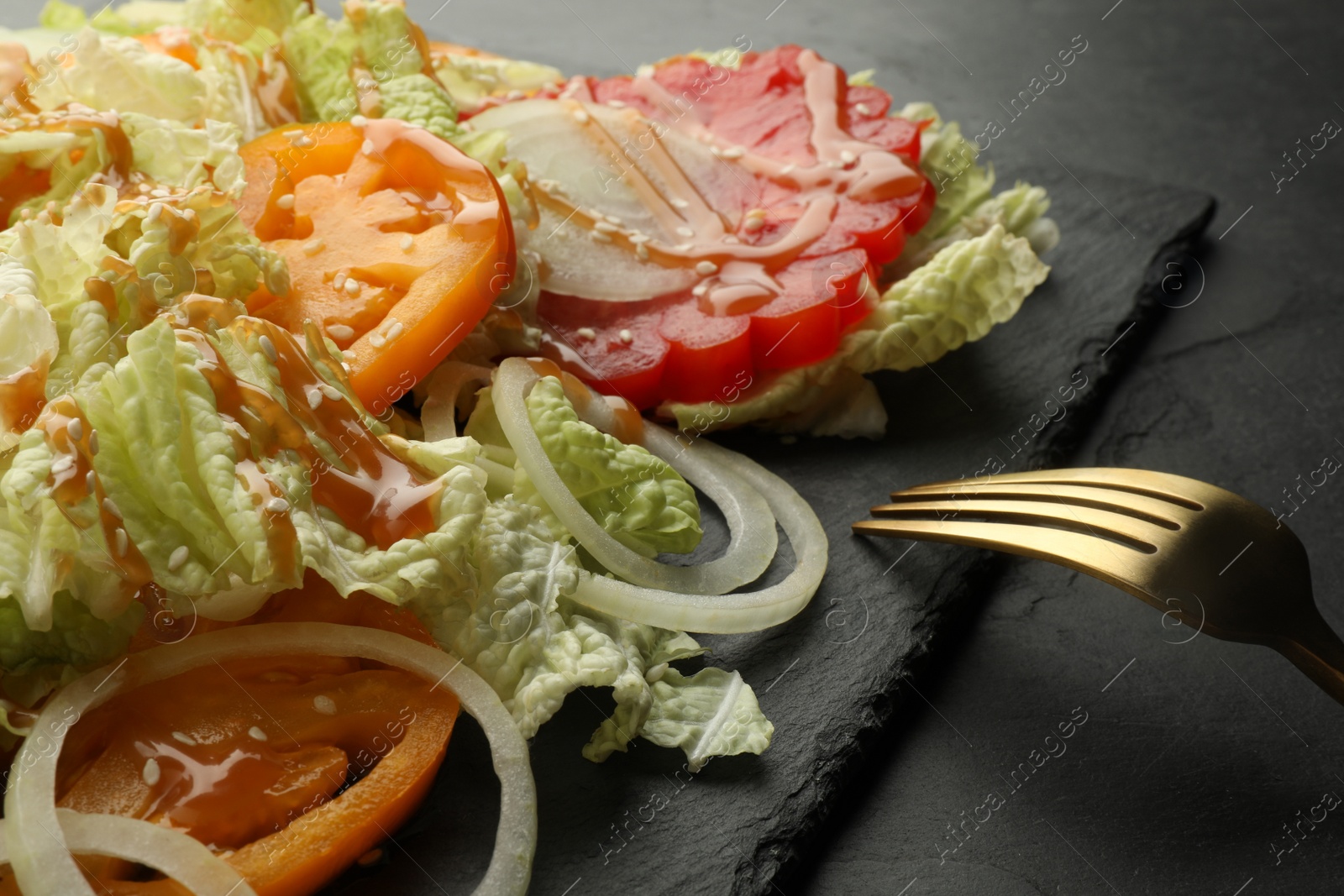 Photo of Delicious salad with Chinese cabbage, tomatoes and onion served on black table, closeup