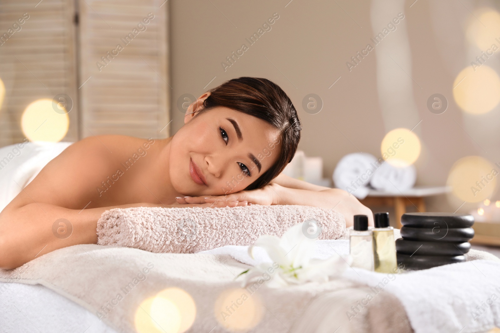 Photo of Beautiful Asian woman lying on massage table in spa salon. Space for text