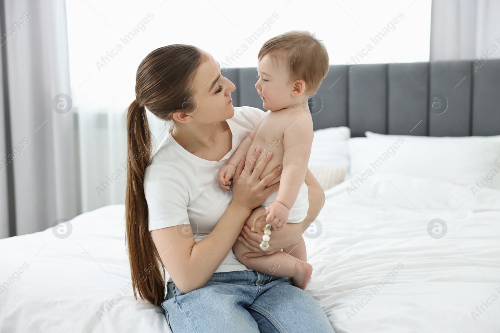 Photo of Mother playing with her baby on bed at home