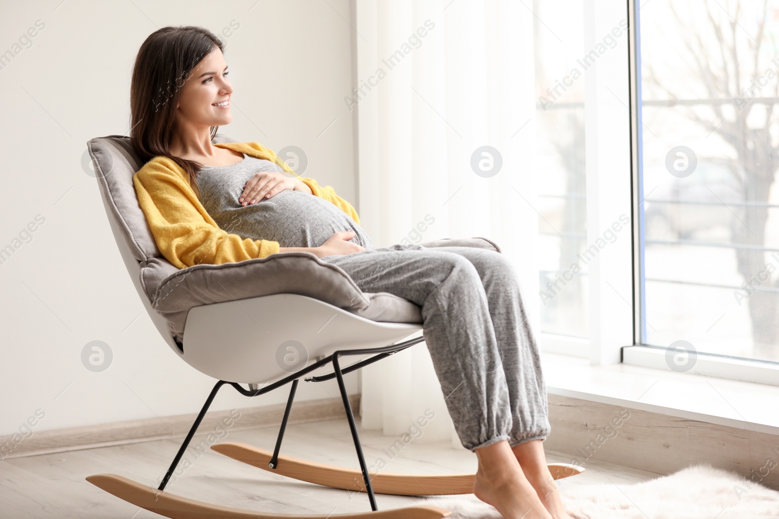 Photo of Young pregnant woman resting in rocking chair at home