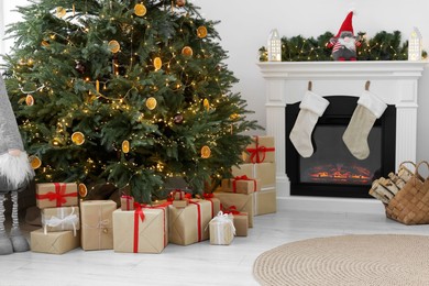 Many different gift boxes under Christmas tree and festive decor in living room