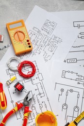 Flat lay composition with wiring diagrams and digital multimeter on grey table