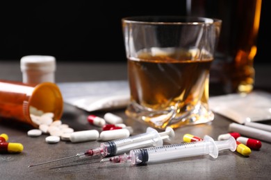 Photo of Alcohol and drug addiction. Syringes, whiskey in glass, pills and cocaine on grey table, closeup