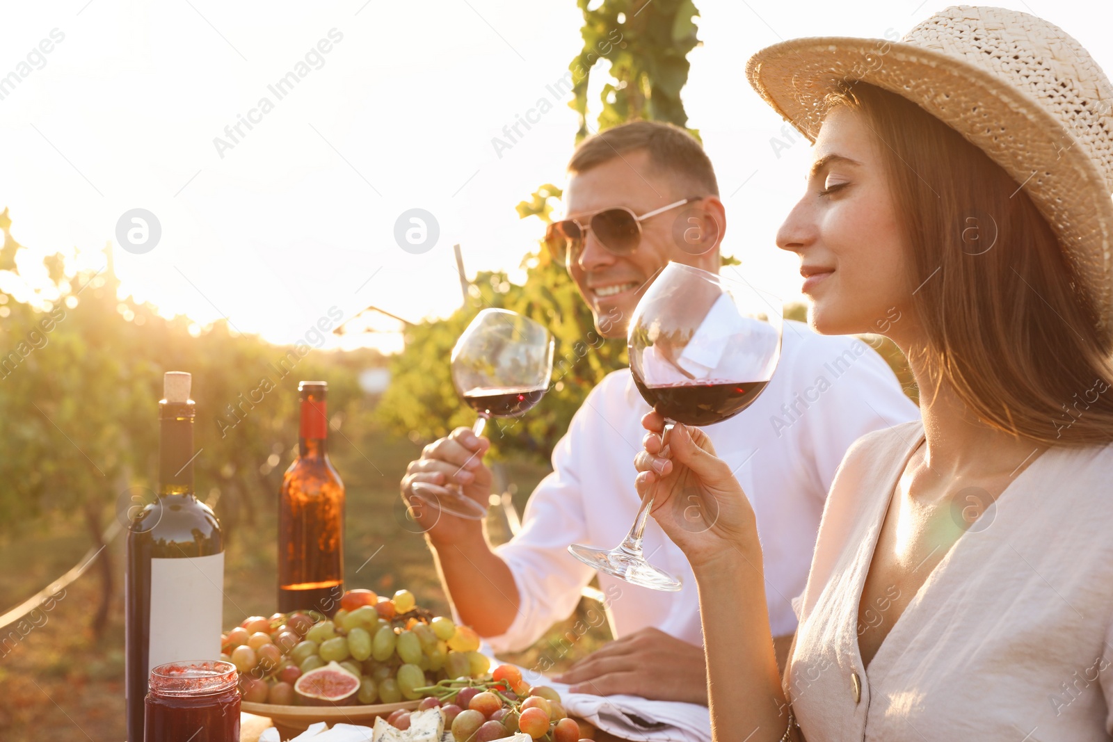 Photo of Couple tasting red wine at vineyard on sunny day