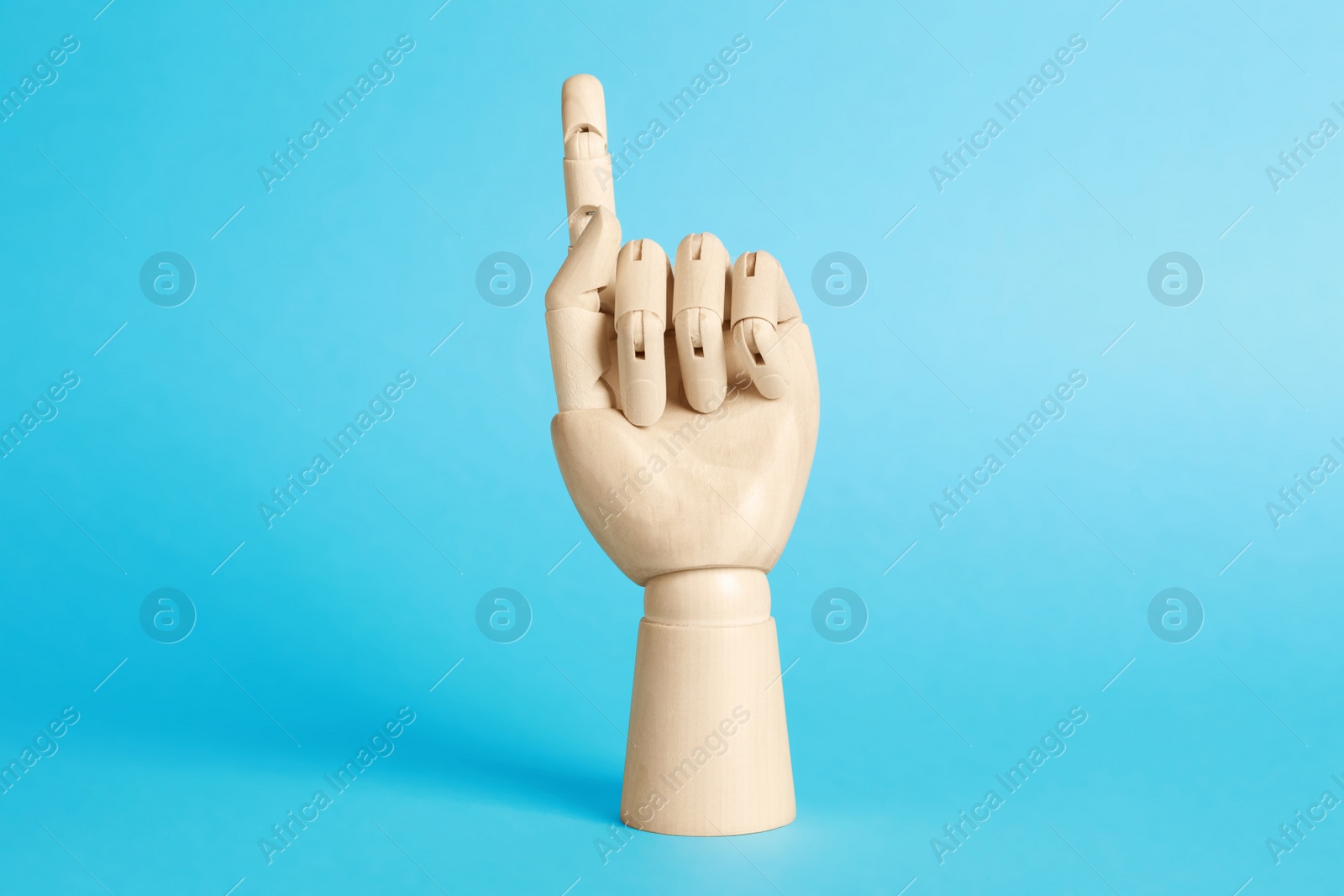 Photo of Wooden hand model on light blue background. Mannequin part