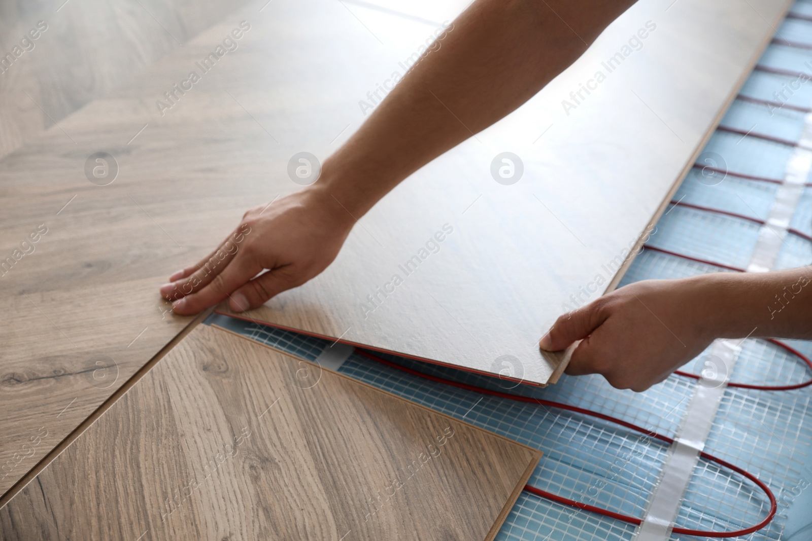 Photo of Professional contractor installing underfloor trace heating system indoors, closeup