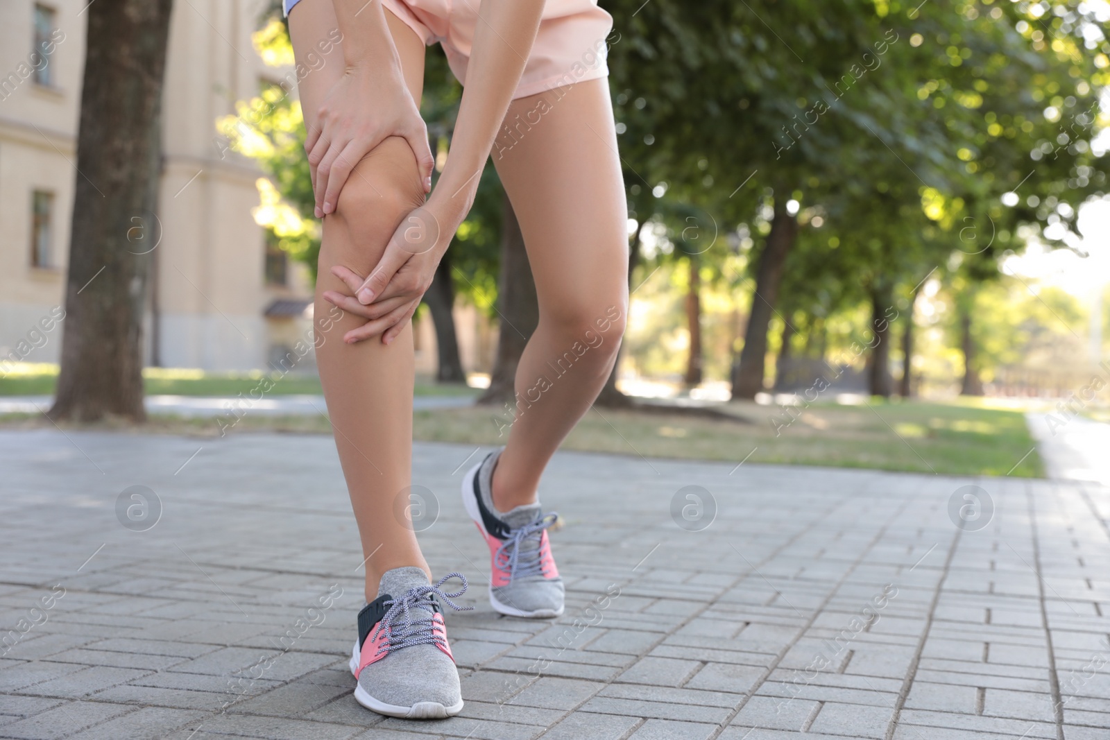 Photo of Young woman having knee problems on city street, closeup