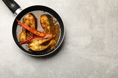 Photo of Tasty fish curry in frying pan on light grey table, top view. Space for text. Indian cuisine