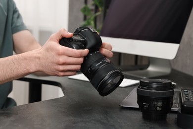 Photographer holding camera at dark table, closeup