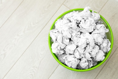 Photo of Metal bin with crumpled paper on floor, top view. Space for text