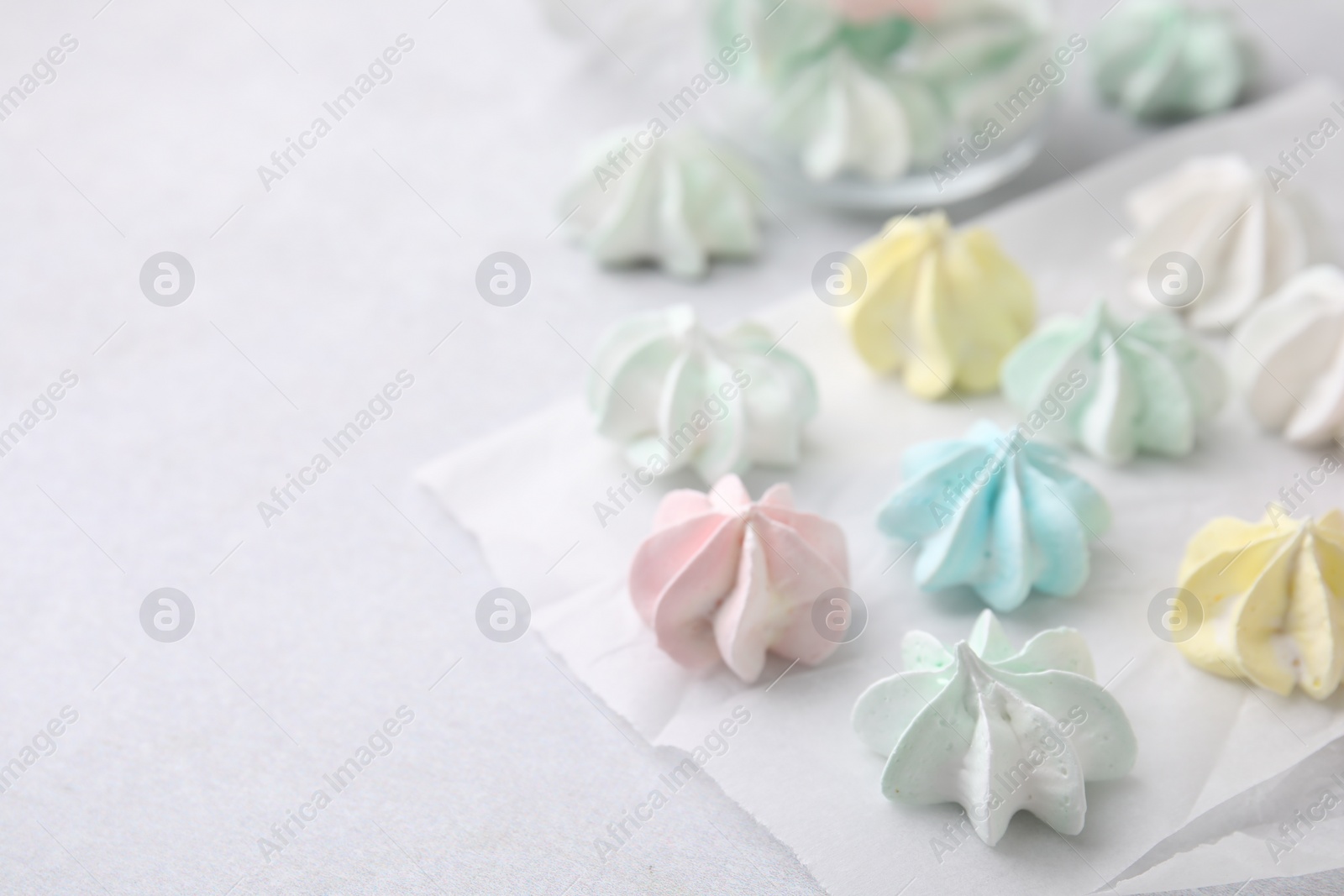 Photo of Tasty meringue cookies on light grey table, closeup. Space for text