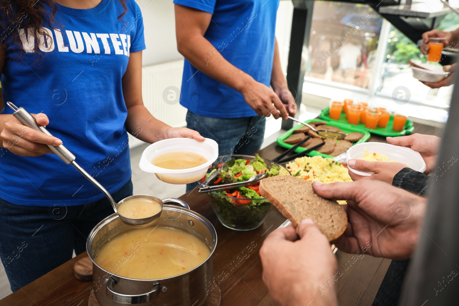 Photo of Volunteers serving food to poor people in charity centre, closeup