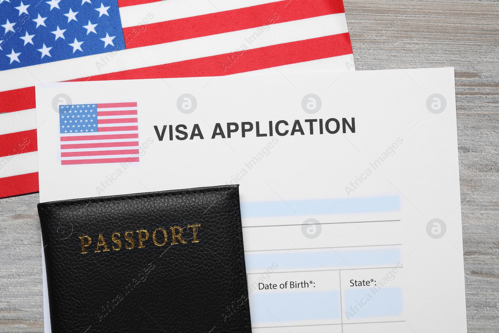 Photo of Immigration to USA. Visa application form, passport and flag on light wooden table, flat lay