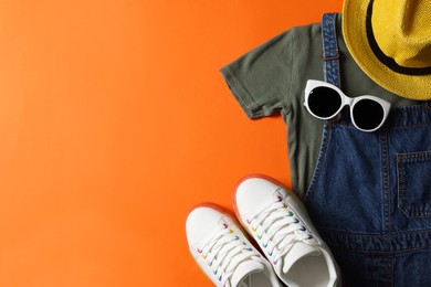 Photo of Stylish child clothes, shoes and accessories on orange background, flat lay. Space for text