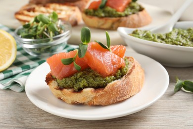 Photo of Delicious bruschetta with salmon and pesto sauce on wooden table