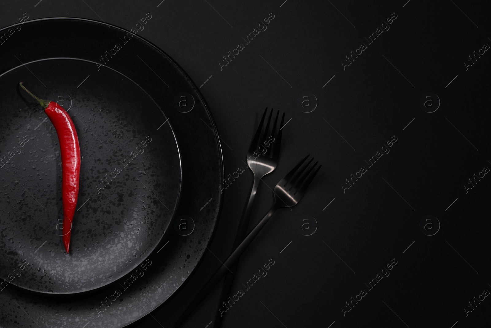 Photo of Stylish table setting. Plates, cutlery and red chilli pepper on black background, top view with space for text