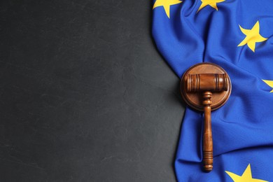 Wooden judge's gavel and flag of European Union on black table, flat lay. Space for text