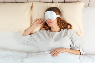 Woman with sleep mask in bed, top view