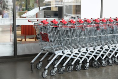 Row of empty metal shopping carts near supermarket outdoors