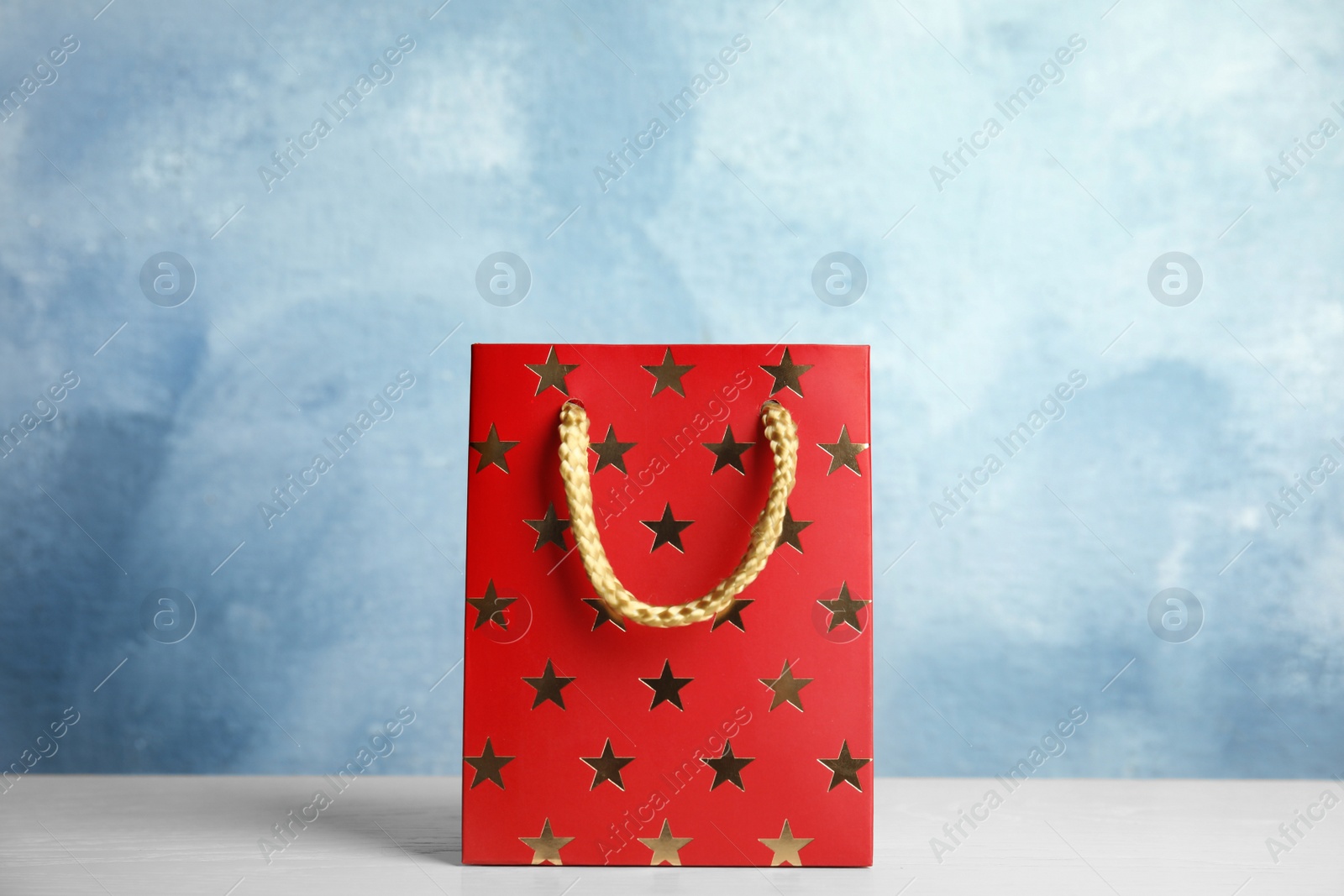 Photo of Red shopping paper bag with star pattern on white table