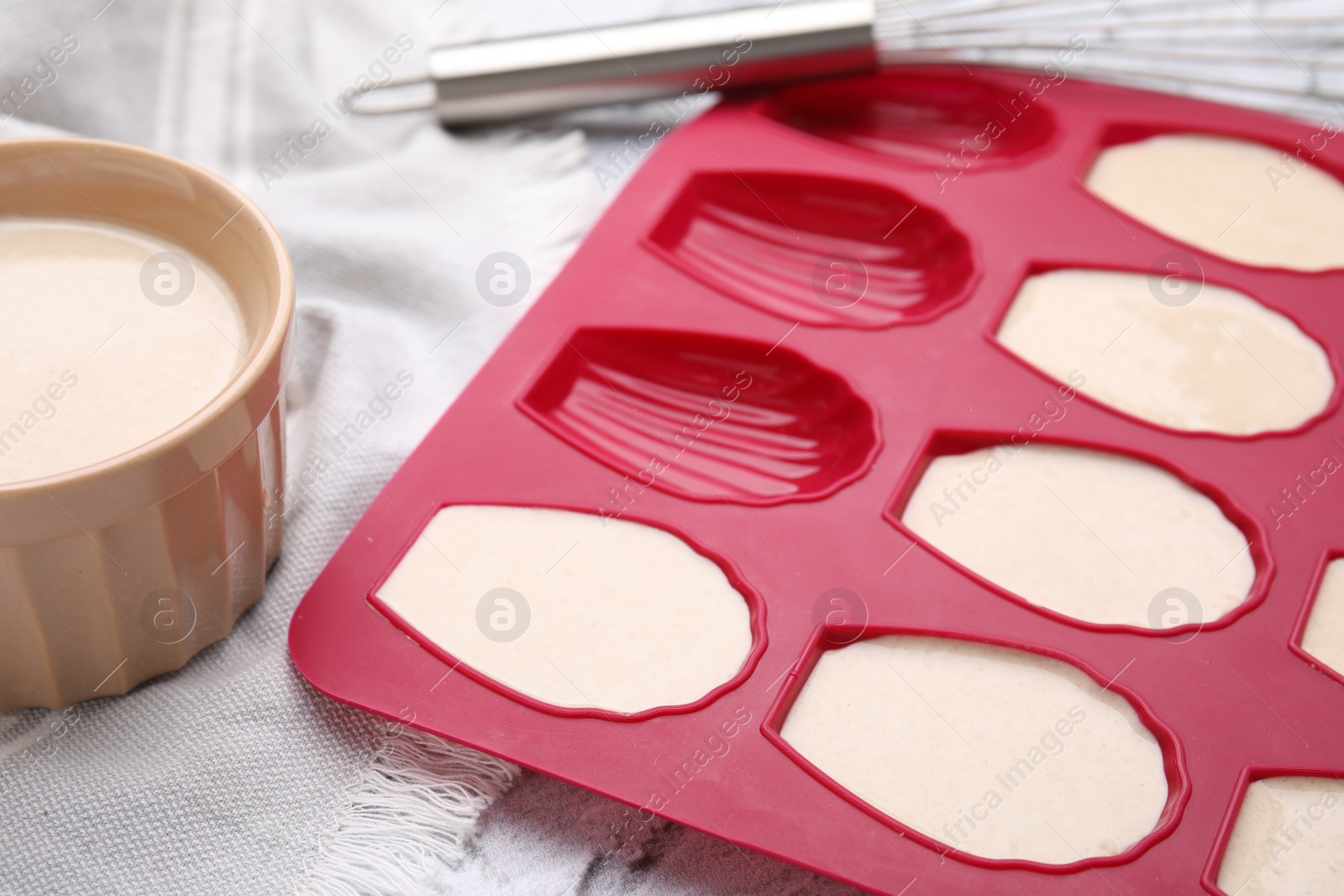 Photo of Baking mold for madeleine cookies with batter on white table, closeup