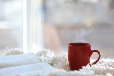 Cup of coffee and book near window in morning. Space for text