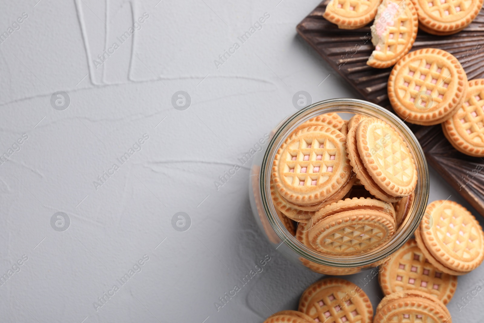 Photo of Tasty sandwich cookies with cream on light grey table, flat lay. Space for text