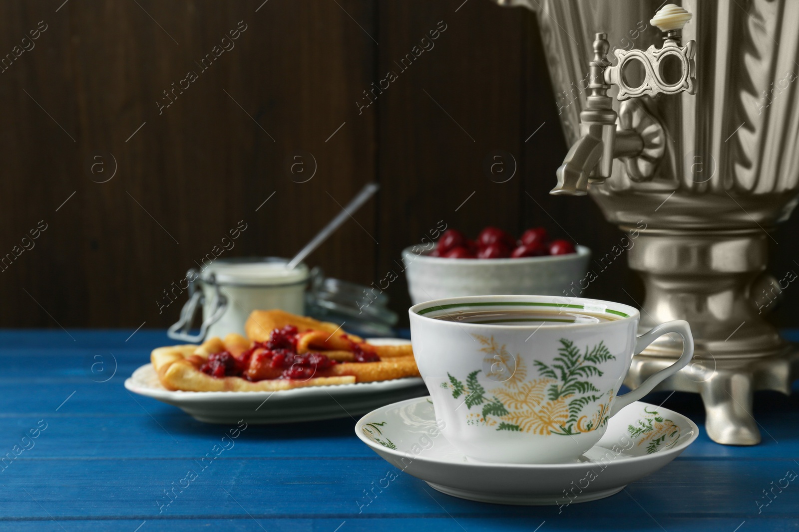 Photo of Aromatic tea, traditional Russian samovar and treats on light blue wooden table. Space for text