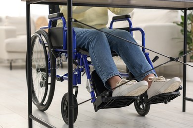 Woman in wheelchair at table indoors, closeup