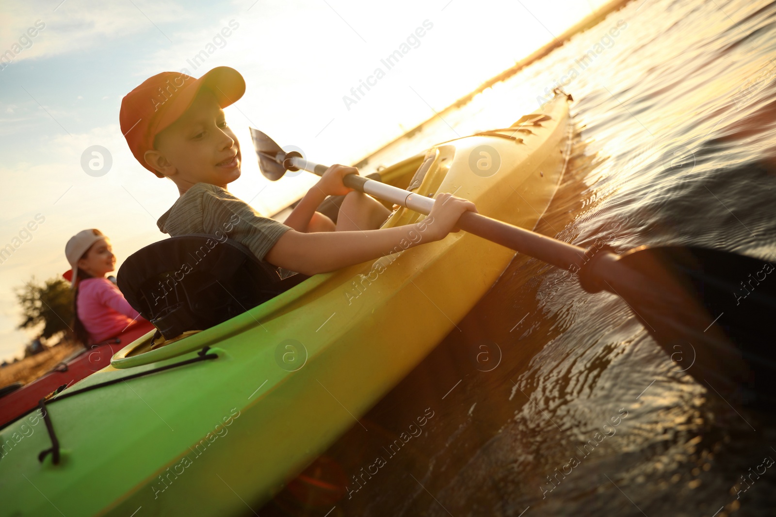 Photo of Happy children kayaking on river at sunset. Summer camp activity