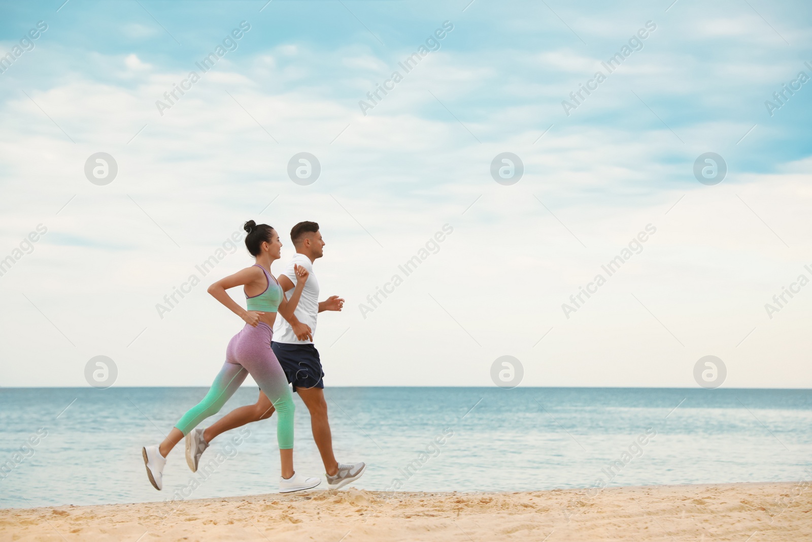 Photo of Couple running together on beach, space for text. Body training