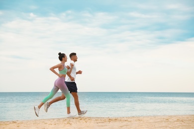 Photo of Couple running together on beach, space for text. Body training