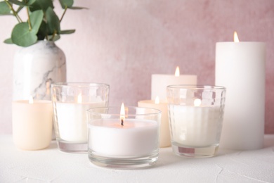 Photo of Burning aromatic candles in holders on table