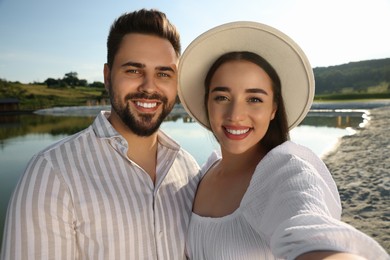 Photo of Romantic date. Beautiful couple making selfie near lake on sunny day