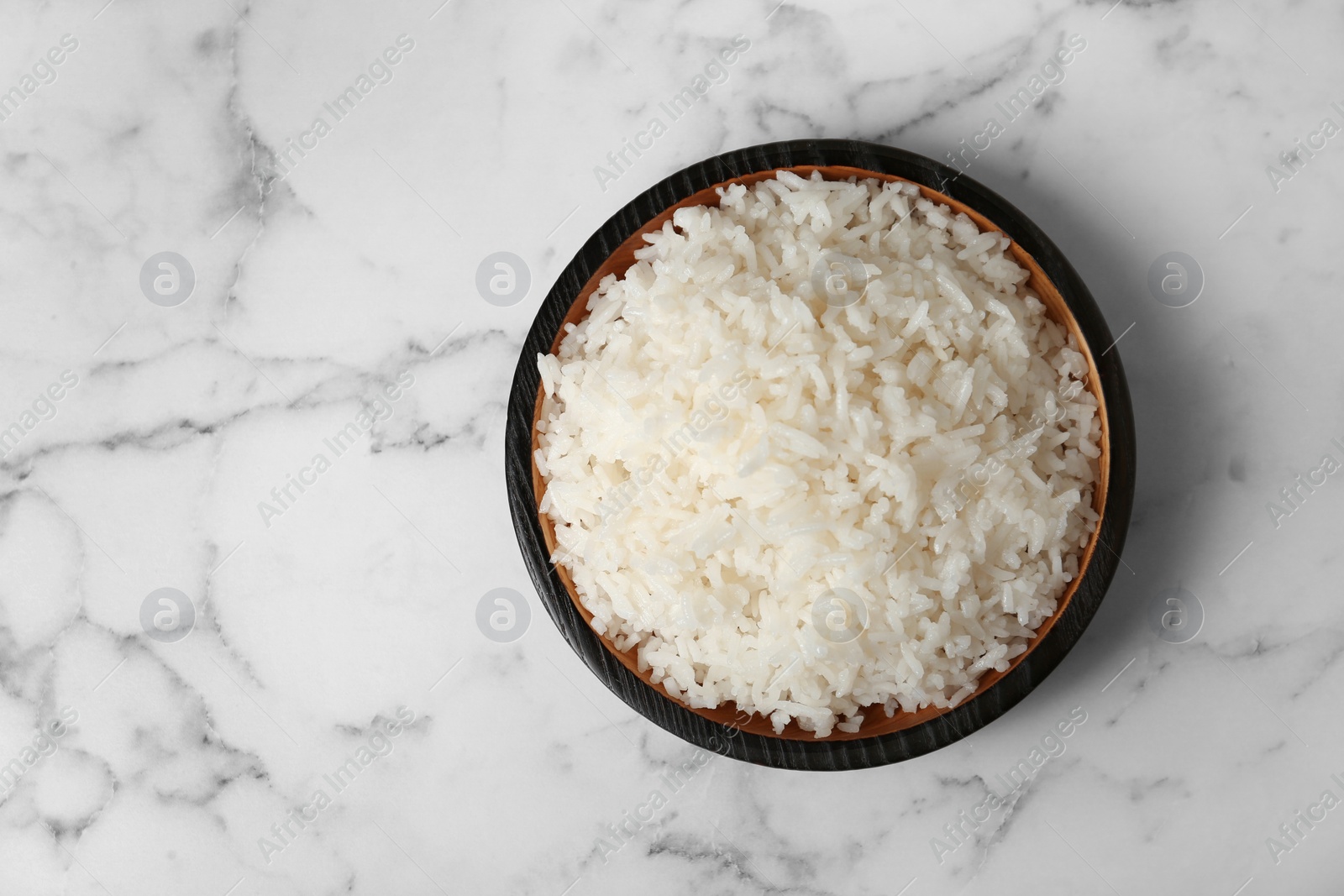 Photo of Bowl of boiled rice on marble background, top view with space for text