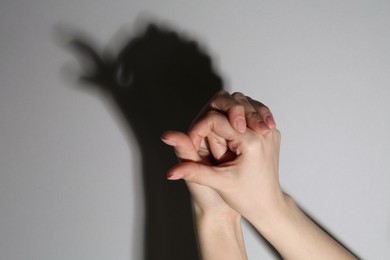 Shadow puppet. Woman making hand gesture like bird on grey background, closeup