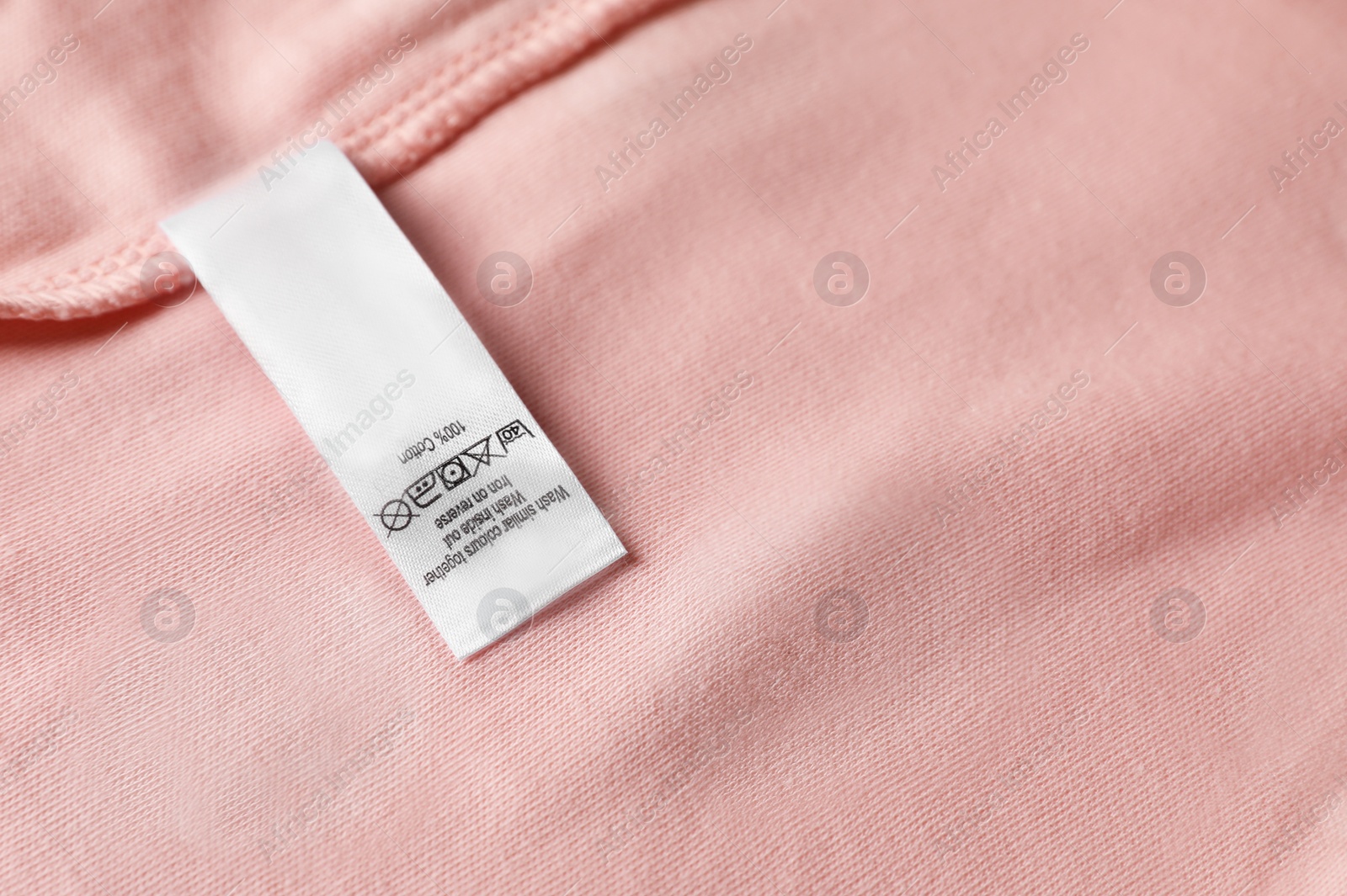 Photo of Clothing label on beautiful pink garment, top view. Space for text