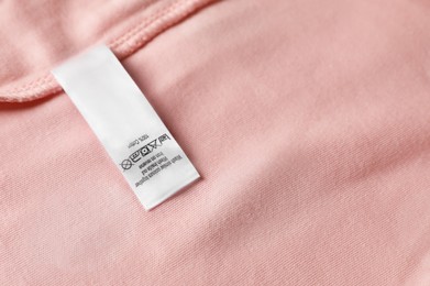 Photo of Clothing label on beautiful pink garment, top view. Space for text