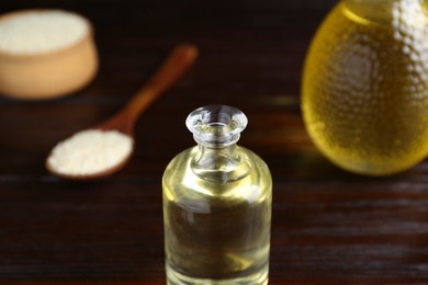 Photo of Fresh sesame oil in glass bottle on wooden table, closeup