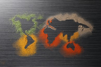 World map of different spices on black wooden table, flat lay