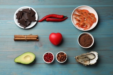 Photo of Natural aphrodisiac. Different food products and heart model on light blue wooden table, flat lay