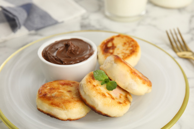 Delicious cottage cheese pancakes with chocolate paste on plate, closeup