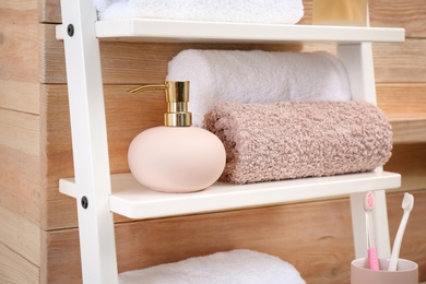 Towels and soap dispenser on shelf in bathroom
