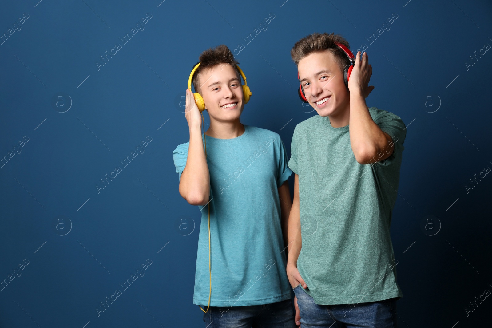 Photo of Teenage twin brothers with headphones on color background. Space for text