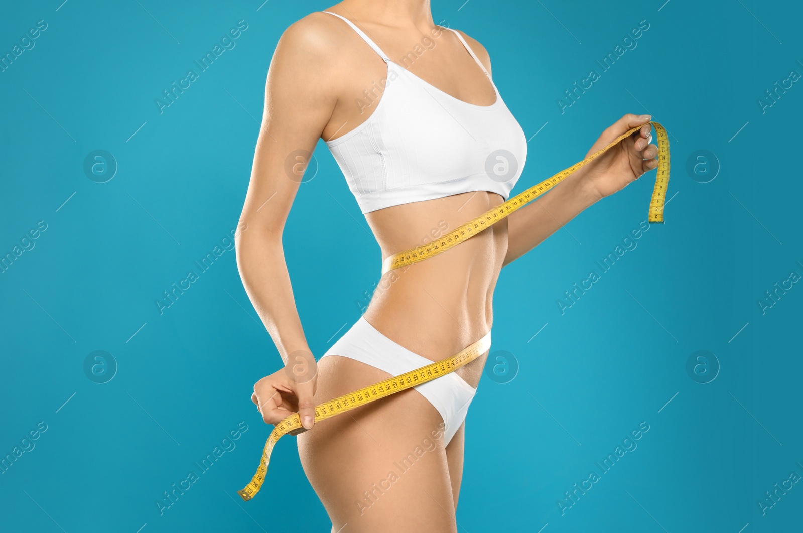 Photo of Slim young woman with smooth gentle skin in underwear measuring body on color background